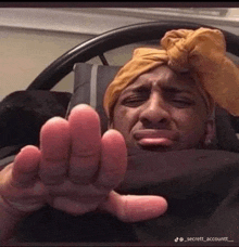 a man wearing a turban is laying in bed and making a funny face with his hands .