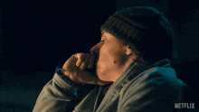a man wearing a beanie and a sweater with netflix written on the bottom right