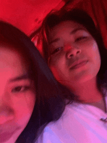a couple of girls are posing for a picture with a red light behind them
