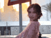 a woman in a pink lace top stands in front of a sign that says no parking