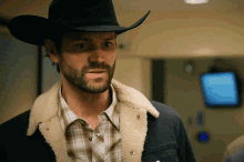 a man wearing a black cowboy hat and a plaid shirt