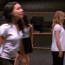 a woman in a white shirt stands in front of empty seats in an auditorium