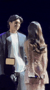 a man in a suit stands next to a woman in a dress