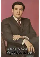 a man in a suit and tie is sitting in a chair with his hands folded