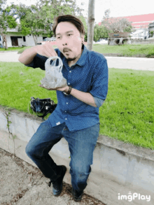 a man in a blue shirt is holding a plastic bag in his hand and eating it