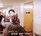 josie and pony are standing in a hallway in front of a door