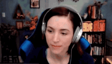 a woman wearing headphones is sitting in a blue chair in front of a bookshelf