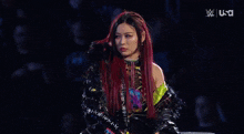 a woman with red hair is holding her hand to her forehead while standing in front of a crowd .