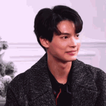 a close up of a young man wearing a black coat and a black shirt .