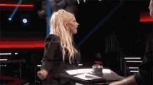 a woman is sitting at a table talking to a man on a television show .