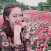 a woman is smiling in front of a field of pink flowers .