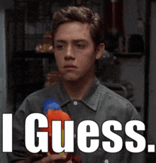 a man in a grey shirt is holding a toy parrot and says " i guess " in white letters