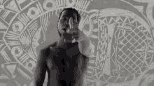 a black and white photo of a shirtless man pointing his finger