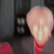 a blurry image of a person 's face with a red scarf around their neck