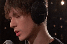 a young man wearing headphones is singing into a microphone in a dark room .