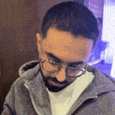 a man with a beard wearing glasses and a gray jacket