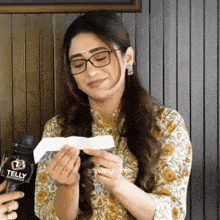 a woman wearing glasses is holding a piece of paper in her hands