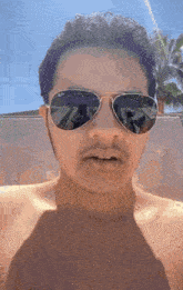a man without a shirt is wearing a pair of aviator sunglasses