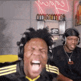 a man wearing headphones is screaming while another man watches .