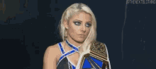 a woman is holding a wrestling championship belt in her hand .