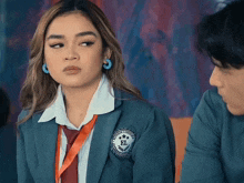 a girl in a school uniform has a badge that says el on it