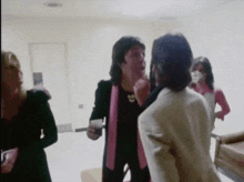 a man in a pink jacket talks to another man in a white jacket
