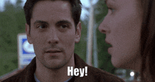 a man and woman are looking at each other and the man is saying hey !