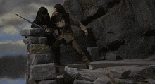 a man with a sword is standing on a rocky ledge
