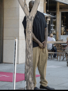 a man standing next to a tree in front of a store that says wine shop