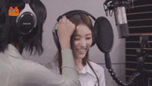 a woman wearing headphones is smiling in front of a microphone with the word cool on it