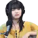a woman wearing headphones and a yellow shirt is talking into a microphone .