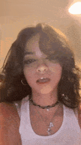 a close up of a woman wearing a white tank top and a necklace .
