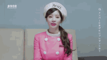 a woman wearing a pink jacket and a white hat with the word twice on it