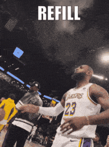 a basketball player with the number 23 on his jersey shakes hands with a fan