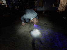 a person kneeling on the ground with a flashlight on the ground