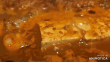 a person is holding tongs over a pan of food with the words made in animotica below it