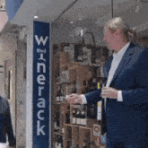 a man in a suit stands in front of a sign that says winerack