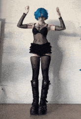 a woman with blue hair is wearing a black outfit and black boots