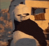 a panda bear wearing a mask is standing in front of a building and looking at the camera .