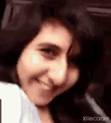 a close up of a woman 's face with a blurred background and a white shirt on .