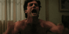 a man without a shirt is screaming with his mouth wide open