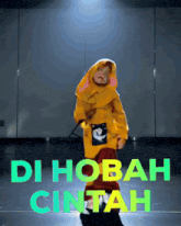 a person in a yellow jacket is dancing with the words di hobah cintah in green