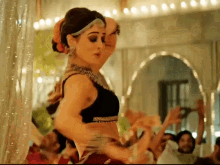a woman in a black top is dancing in front of a crowd of people in a room .