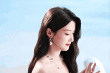 a woman wearing a pearl necklace is looking down at something