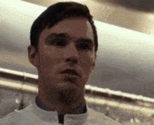 a close up of a man 's face wearing a white jacket
