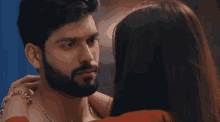 a man with a beard and a woman in a red dress look at each other