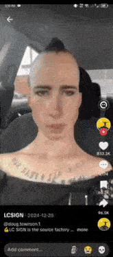 a man with a mohawk and a tattoo on his neck is sitting in a car