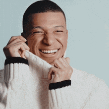 a man wearing a white sweater with black stripes is smiling