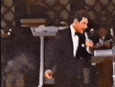 two men in tuxedos are dancing on a stage in front of a crowd of people .