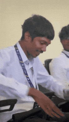 a man in a white shirt with a blue lanyard around his neck looks down